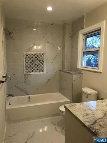 a bathroom with a granite countertop sink a mirror and a bathtub
