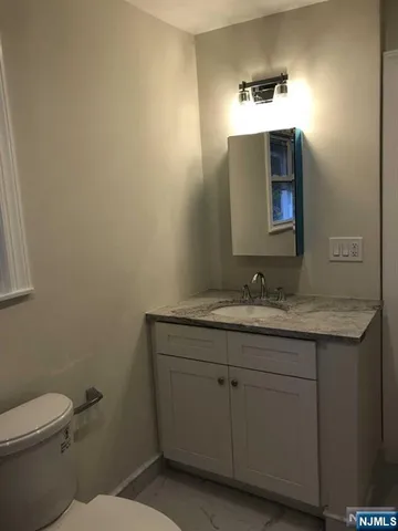 a bathroom with a granite countertop toilet sink and mirror