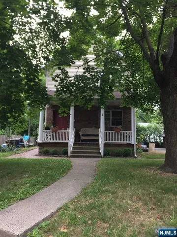 a front view of a house with garden and trees