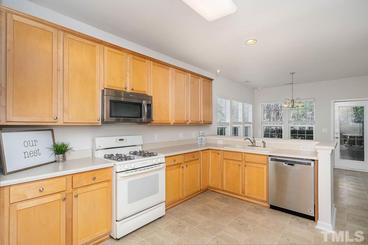7468 Silver View Lane Raleigh, NC 27613 - Photo 5 of 31 a kitchen with stainless steel appliances granite countertop a stove top oven a sink dishwasher and white cabinets with wooden floor