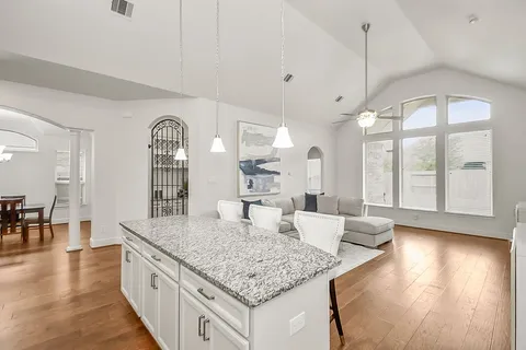 a kitchen with stainless steel appliances granite countertop a sink a stove and island with wooden floor