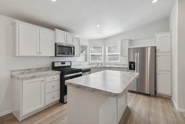a kitchen with stainless steel appliances granite countertop a sink stove and refrigerator