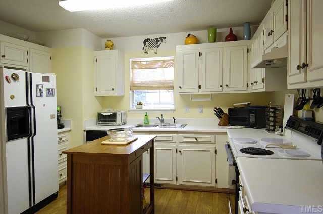 4513 Timberhurst Drive Raleigh, NC 27612 - Photo 4 of 10 a kitchen with a sink a stove a refrigerator and cabinets