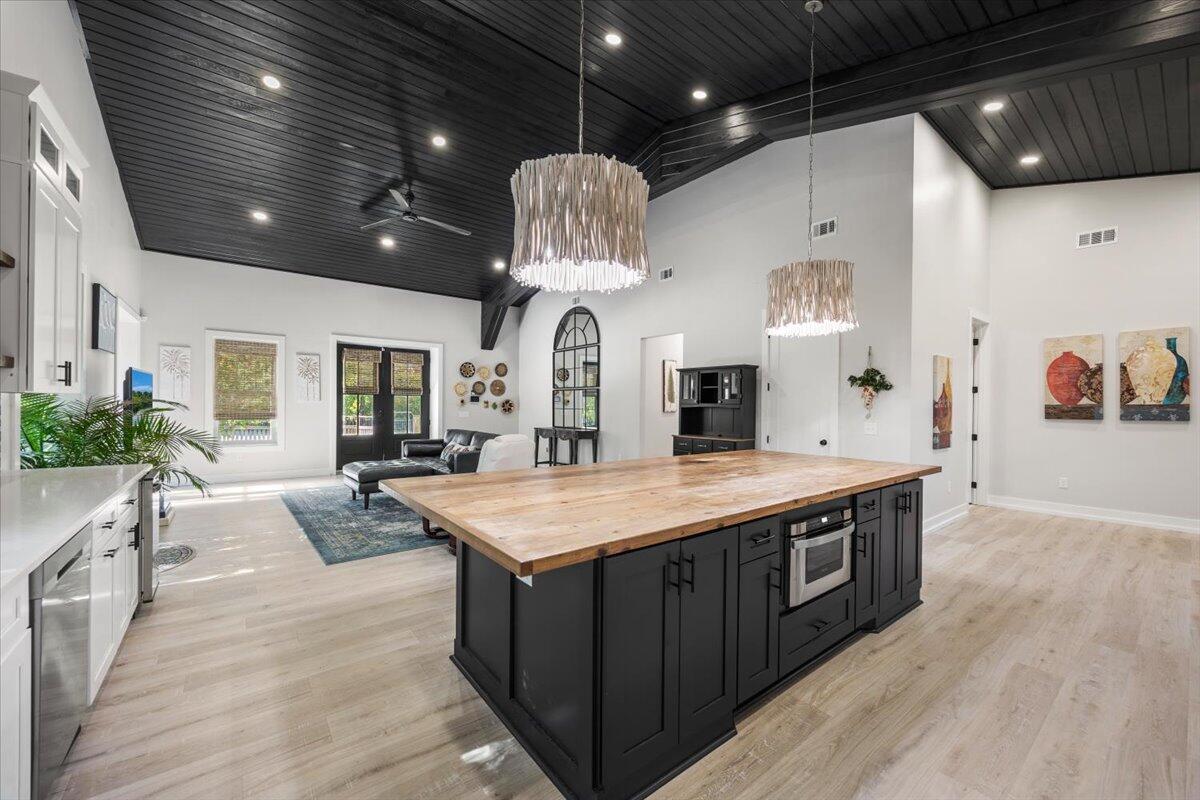 3574 Bob Tolbert Road Navarre, FL 32566 - Photo 12 of 67 a large kitchen with stainless steel appliances granite countertop a sink dishwasher a stove and a dining table with wooden floor