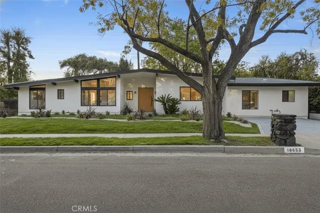 a front view of a house with a garden and trees