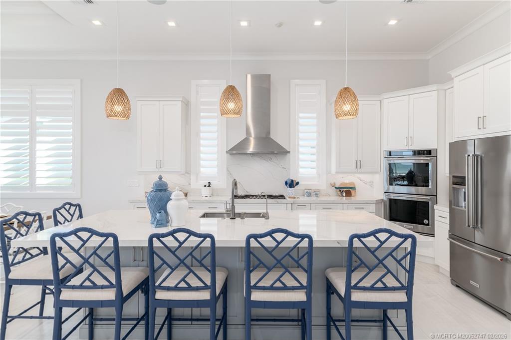 4824 Watersong Way Fort Pierce, FL 34949 - Photo 18 of 65 a kitchen with stainless steel appliances a refrigerator a stove a sink cabinets and a dining table with chairs