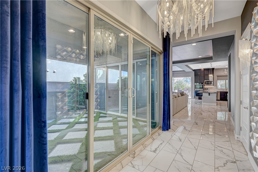 3943 Reyes Avenue Las Vegas, NV 89141 - Photo 23 of 95 Sliding glass doors open to a serene backyard with stepping stones amidst lush green grass, visible from a spacious interior.