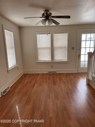 an empty room with wooden floor and windows