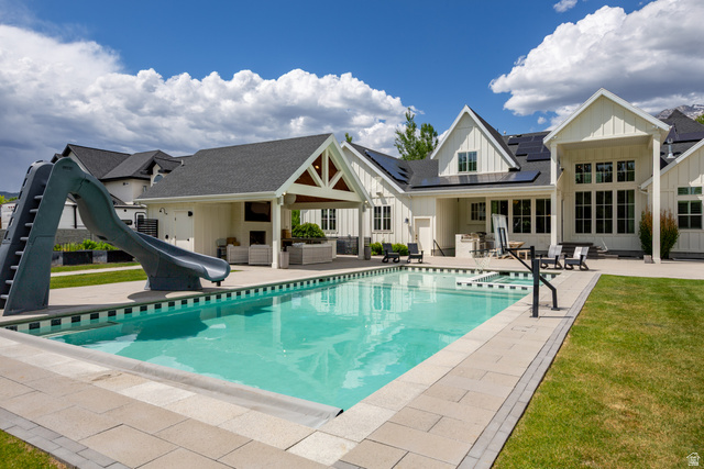 630 East Center Street Alpine, UT 84004 - Photo 108 of 115 Expansive outdoor living area featuring a rectangular swimming pool with integrated spa and pool slide, complemented by a covered patio with exposed beam detailing and an outdoor fireplace