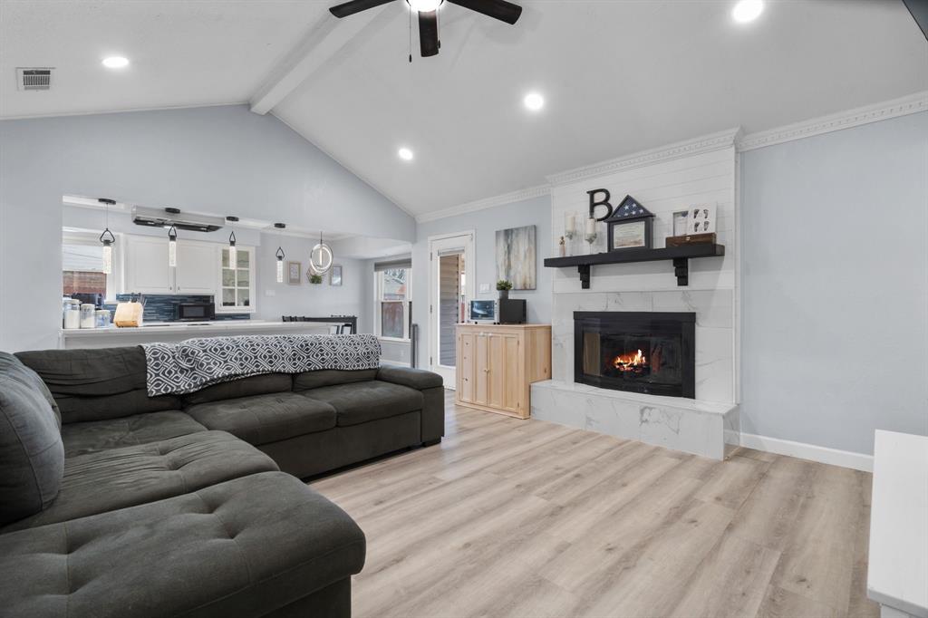 7629 Cedarhill Road Watauga, TX 76148 - Photo 7 of 33 Vaulted ceiling living area featuring a fireplace with a white shiplap and marbled-look surround, recessed lighting, wood-finish flooring, and a ceiling fan