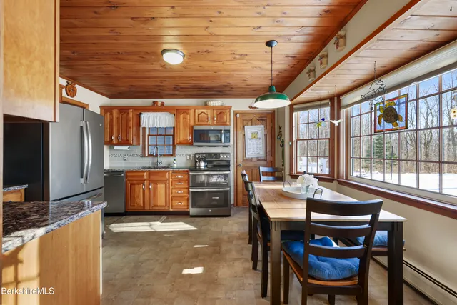 a kitchen with stainless steel appliances kitchen island granite countertop a table chairs and a refrigerator