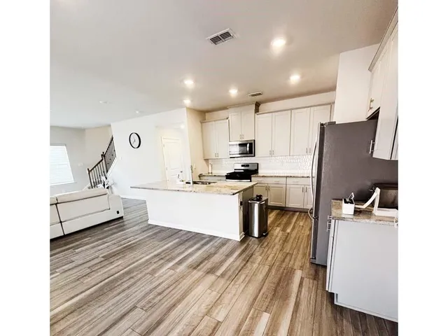 a kitchen with a sink and a stove top oven with wooden floor