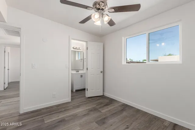 an empty room with wooden floor and a ceiling fan