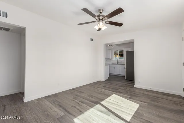 an empty room with wooden floor and a ceiling fan