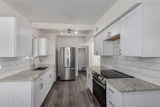 a kitchen with granite countertop a sink stove and refrigerator