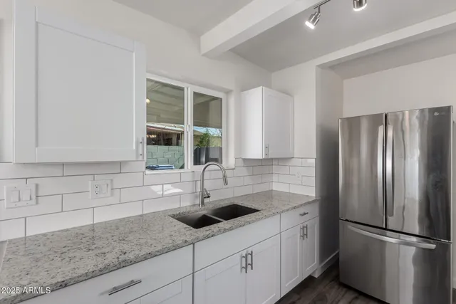 a kitchen with stainless steel appliances granite countertop a sink and a refrigerator