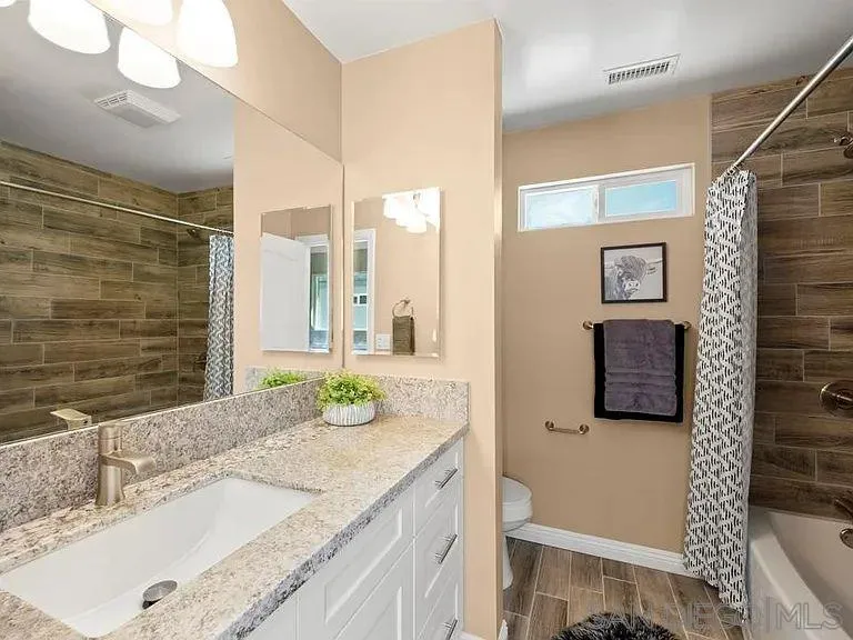 909 Concepcion Avenue Spring Valley, CA 91977 - Photo 22 of 27 a bathroom with a granite countertop sink and a mirror