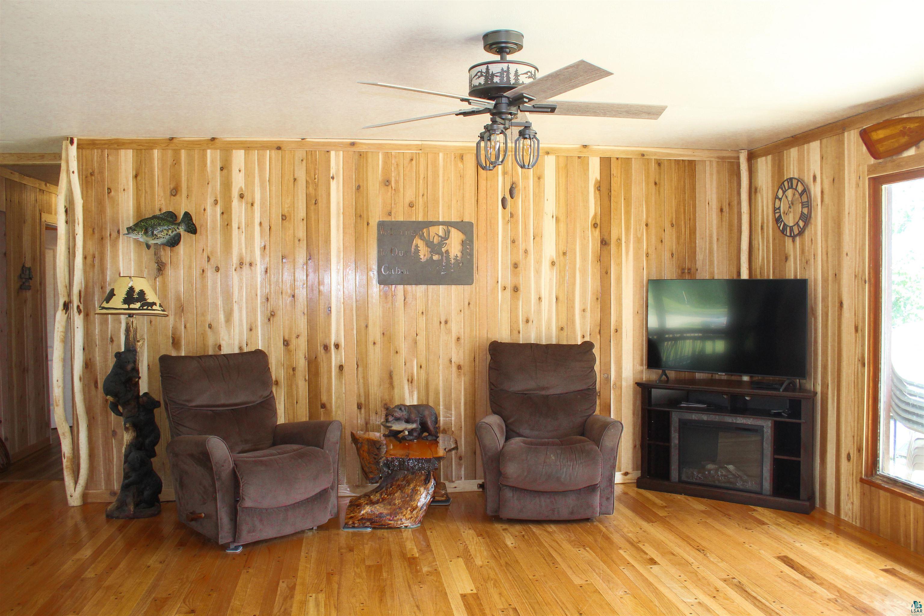 444 Fernberg Road, Unit 11 Ely, MN 55731 - Photo 10 of 19 Living area featuring wood walls, ceiling fan, a skylight, and wood finished floors