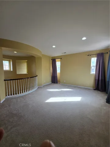 a view of an empty room with a window and a kitchen