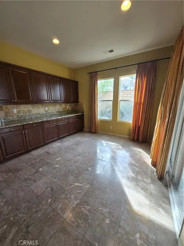 a large kitchen with kitchen island a large counter top a sink a window and stainless steel appliances