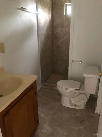 a view of a refrigerator in kitchen and an empty room in wooden floor