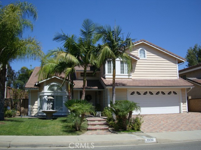 a front view of a house with a yard and potted plants