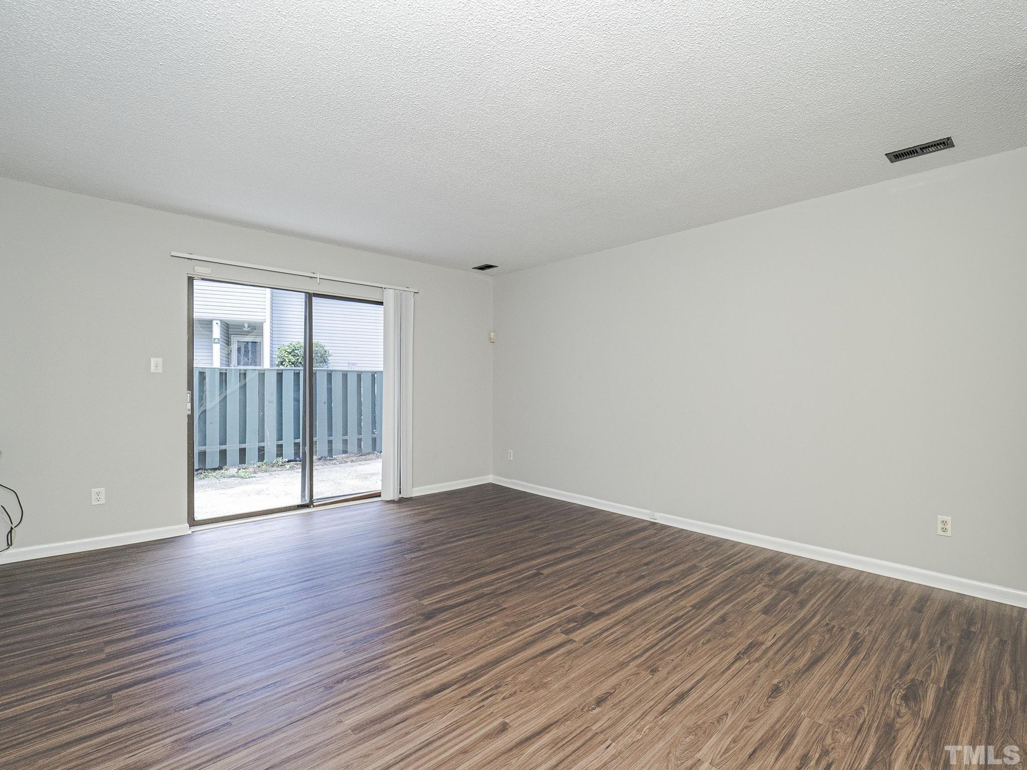 4705 Walden Pond Drive, Unit D Raleigh, NC 27604 - Photo 8 of 24 a view of an empty room with wooden floor and a window