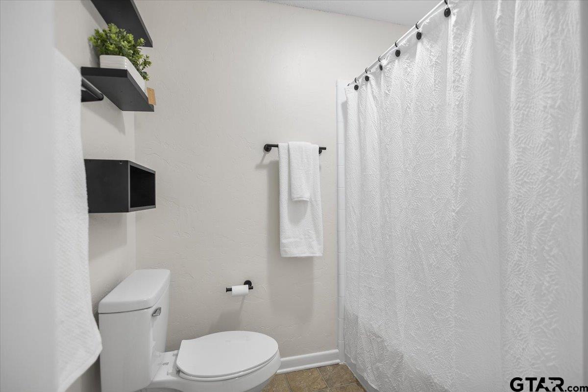 2320 Grangeway Road Marshall, TX 75672 - Photo 30 of 48 a white toilet sitting next to a shower curtain