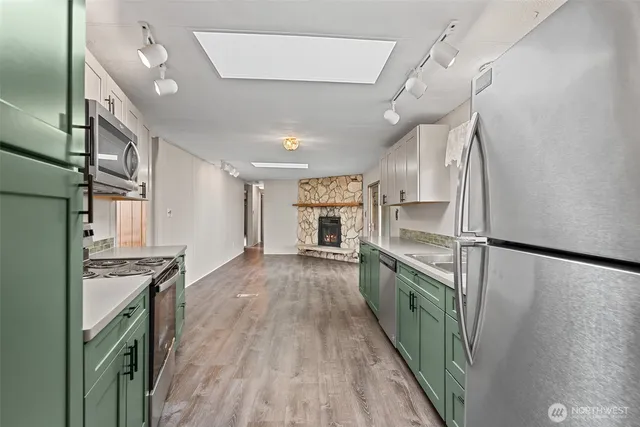 a kitchen with granite countertop a refrigerator a sink dishwasher a stove and white cabinets with wooden floor