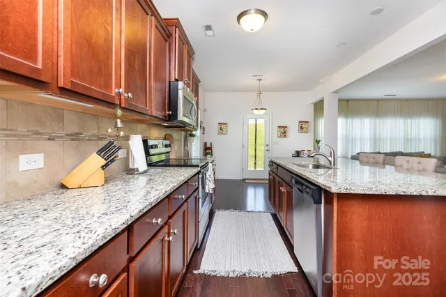a kitchen with stainless steel appliances granite countertop a sink stove and cabinets