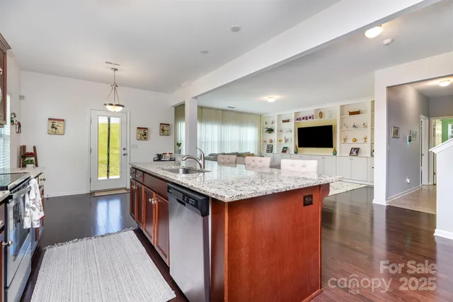 a kitchen with stainless steel appliances kitchen island granite countertop a sink stove and cabinets