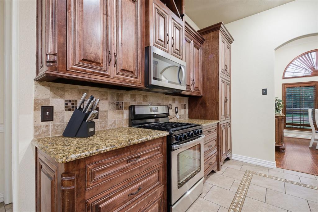 603 Cedar Drive Pilot Point, TX 76258 - Photo 5 of 39 Kitchen featuring wood cabinetry, granite countertops, tile backsplash, and a stainless steel oven/range with a microwave