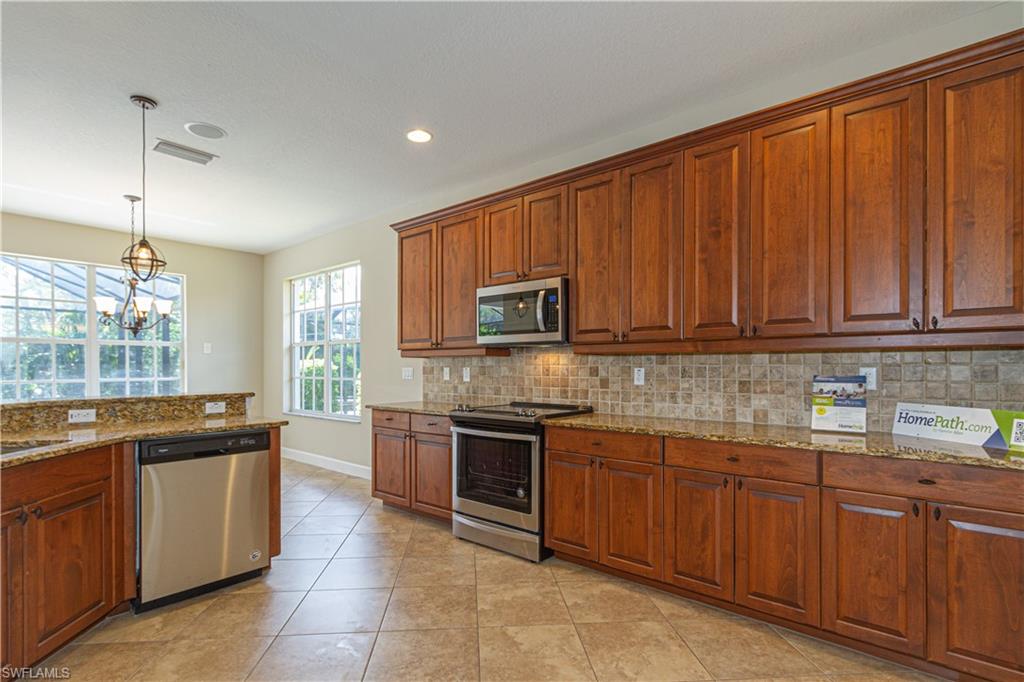 9172 Quartz Lane Naples, FL 34120 - Photo 4 of 25 a kitchen with stainless steel appliances granite countertop wooden cabinets a sink and dishwasher