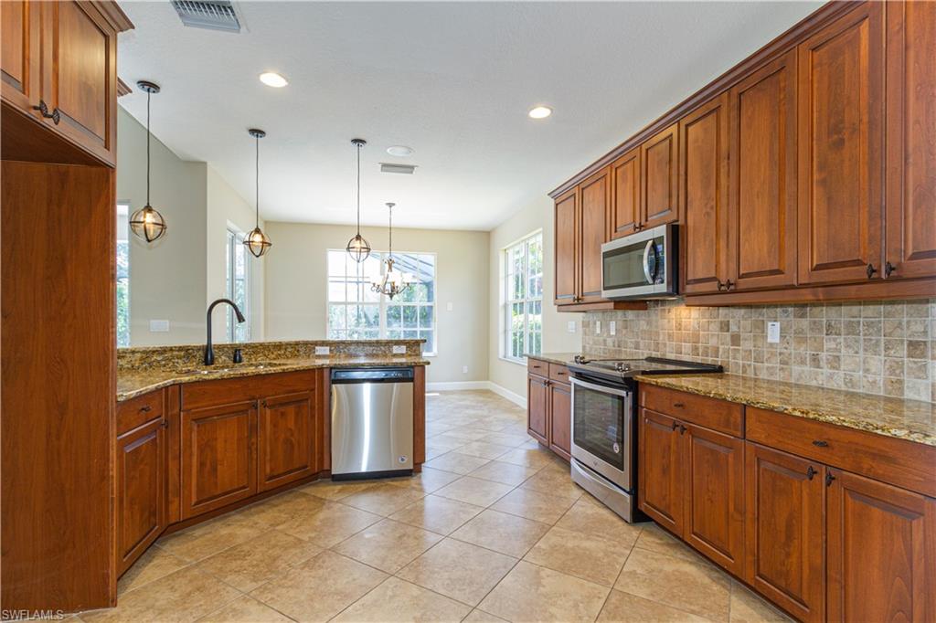 9172 Quartz Lane Naples, FL 34120 - Photo 5 of 25 a large kitchen with stainless steel appliances granite countertop a stove top oven a sink dishwasher and a refrigerator