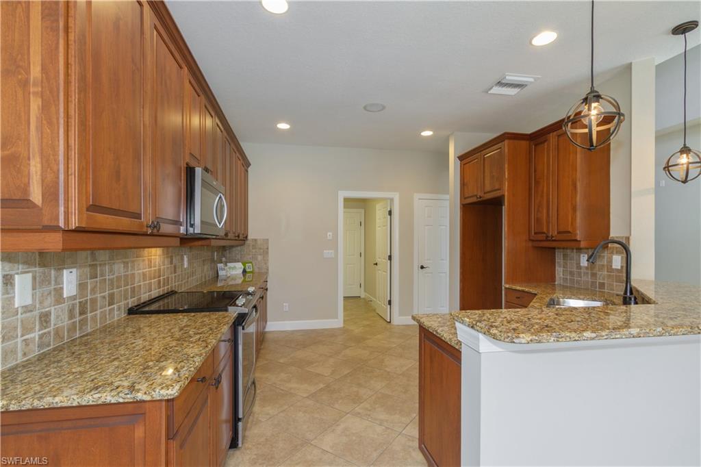 9172 Quartz Lane Naples, FL 34120 - Photo 6 of 25 a kitchen with stainless steel appliances granite countertop wooden cabinets a sink and a granite counter tops