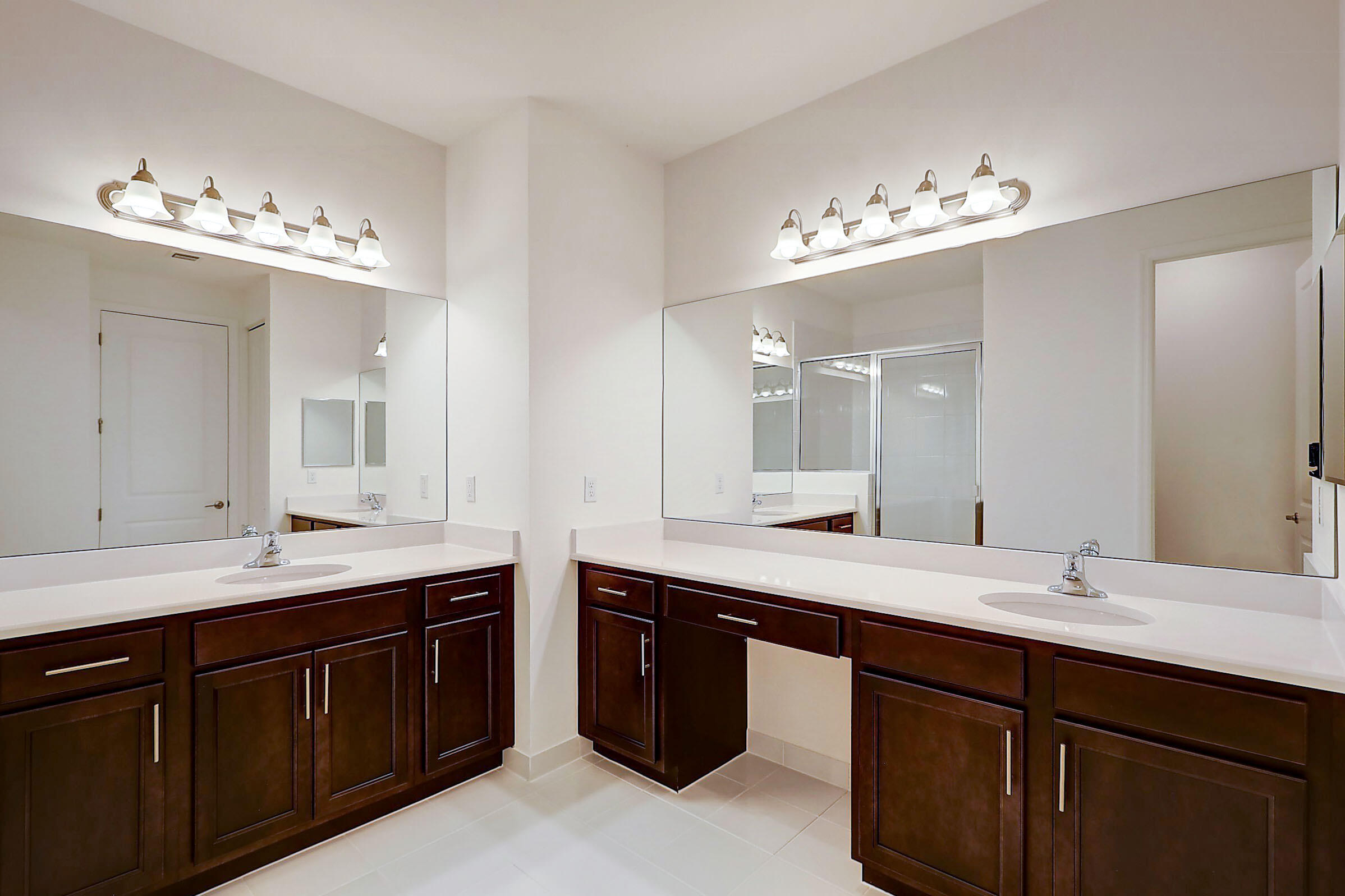 13549 Southwest Oceanus Boulevard Port St. Lucie, FL 34987 - Photo 12 of 30 a bathroom with double vanity sinks a vanity a lamp and a mirror