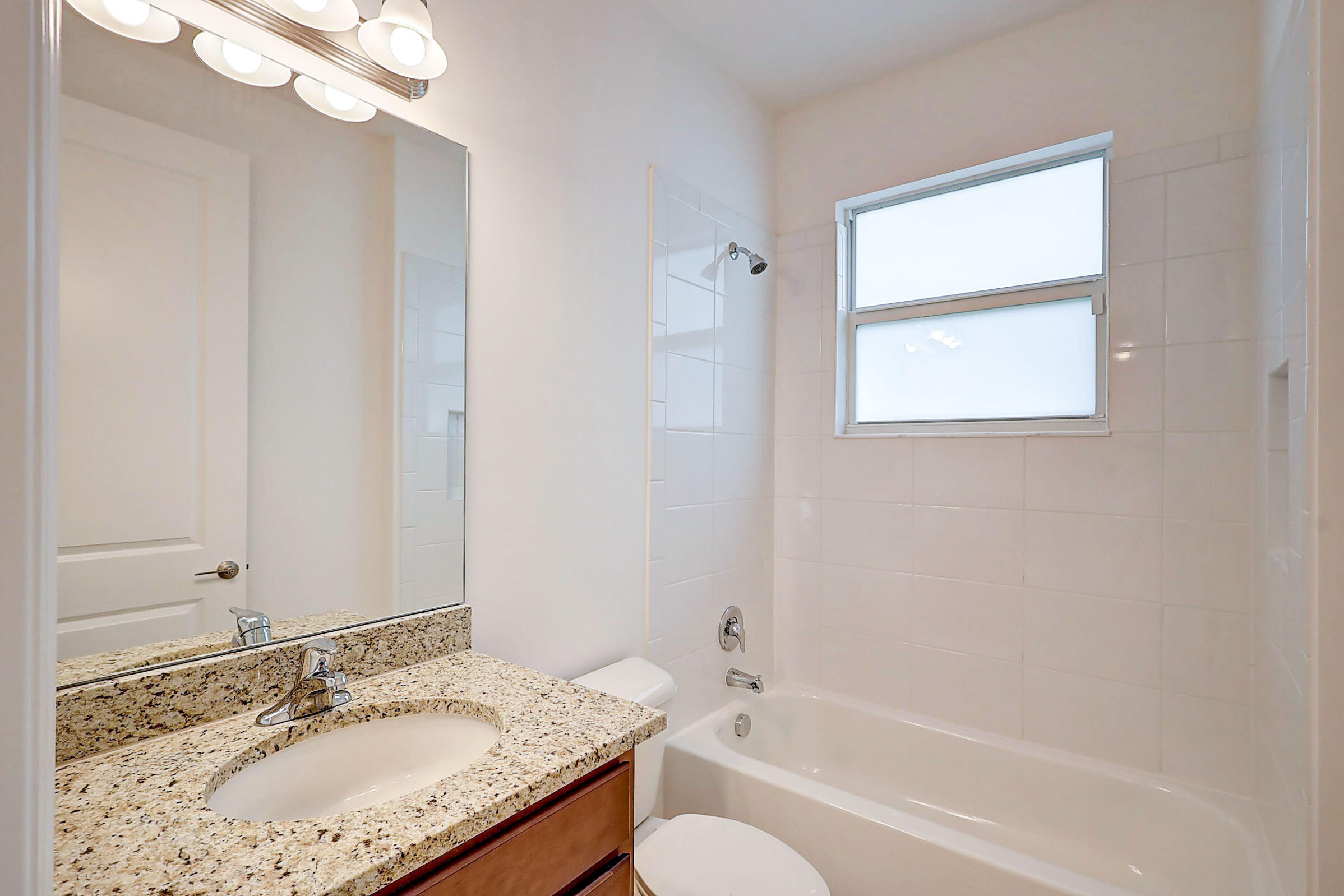 13549 Southwest Oceanus Boulevard Port St. Lucie, FL 34987 - Photo 17 of 30 a bathroom with a granite countertop sink mirror and a bathtub