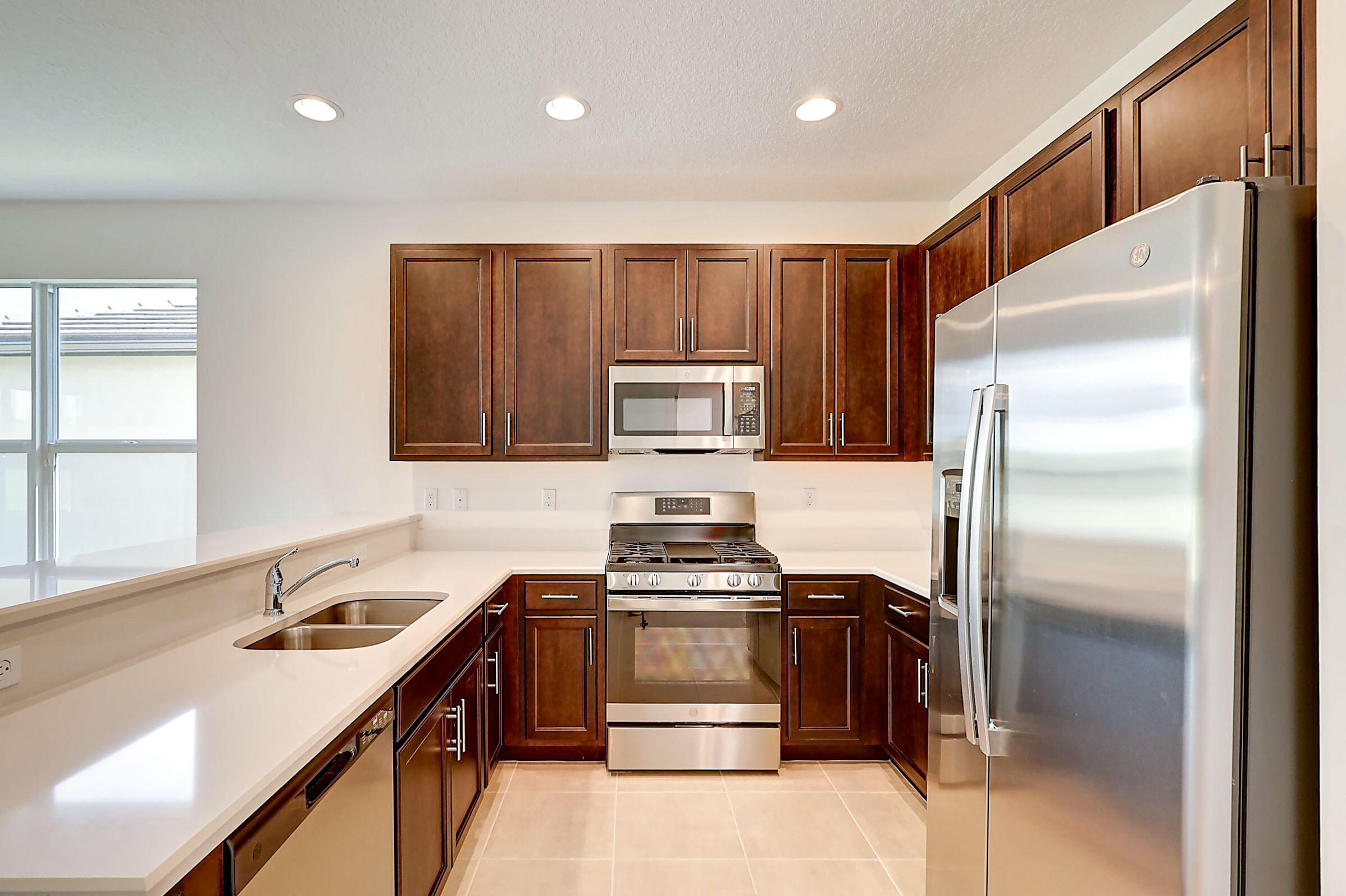 13549 Southwest Oceanus Boulevard Port St. Lucie, FL 34987 - Photo 20 of 30 a kitchen with kitchen island stainless steel appliances cabinets a sink and a stove