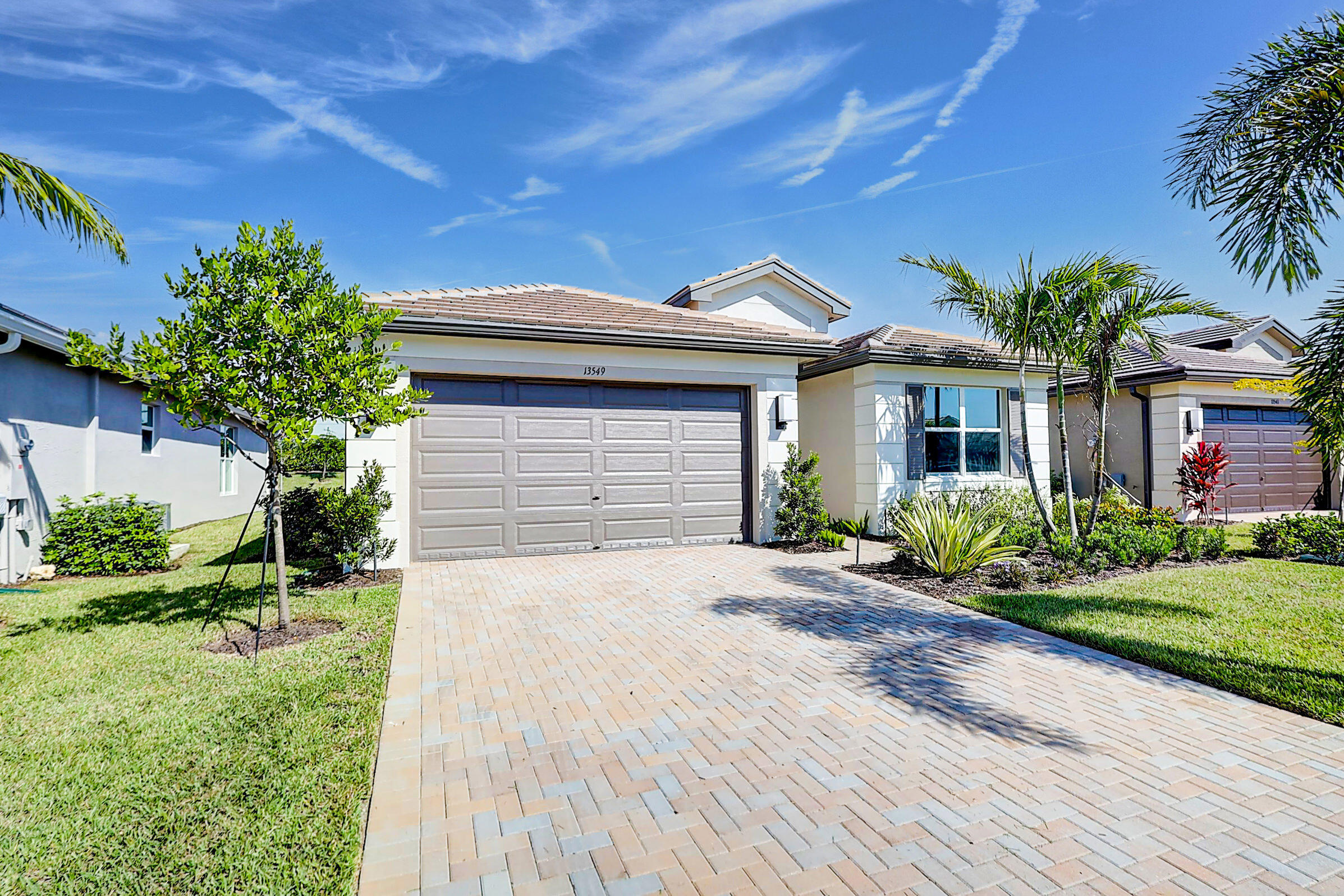 13549 Southwest Oceanus Boulevard Port St. Lucie, FL 34987 - Photo 2 of 30 a front view of a house with a yard and potted plants