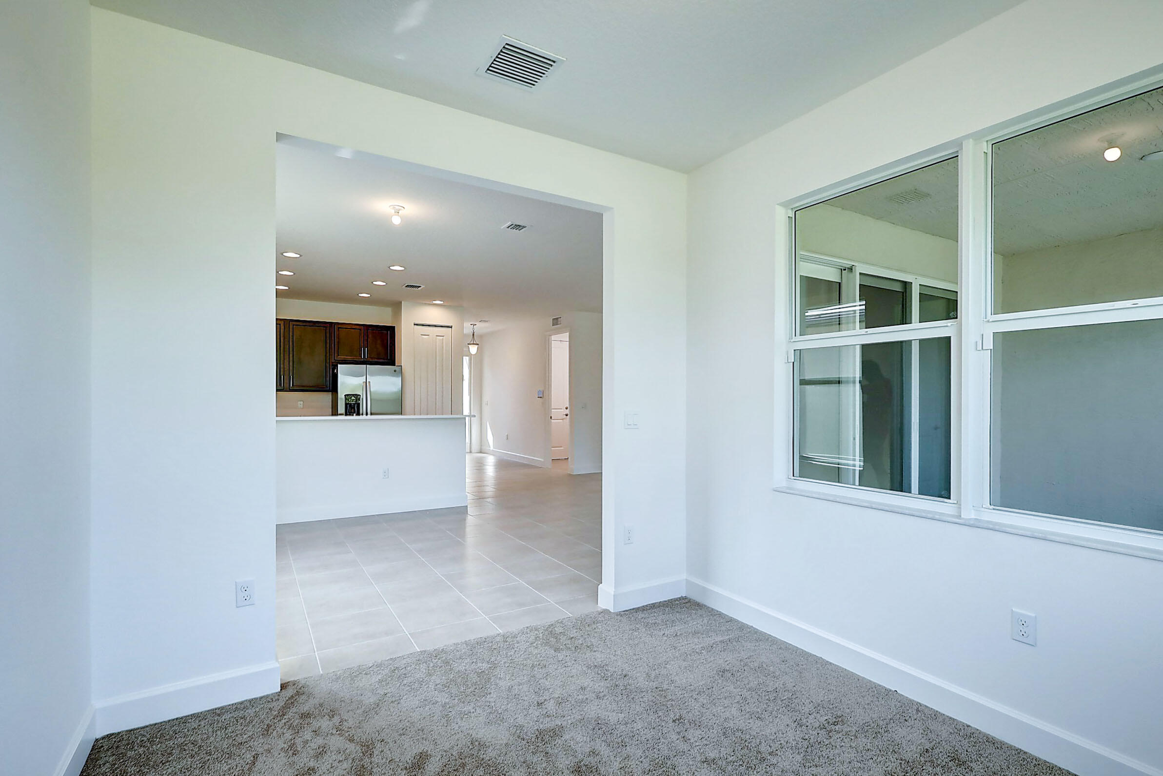 13549 Southwest Oceanus Boulevard Port St. Lucie, FL 34987 - Photo 23 of 30 an empty room with kitchen and entrance
