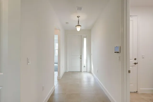 a view of a hallway with wooden floor and a bathroom