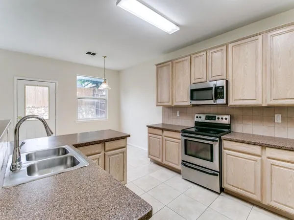 a kitchen with granite countertop a stove a sink and a microwave