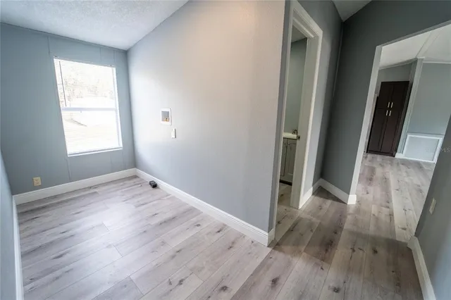 an empty room with wooden floor and windows