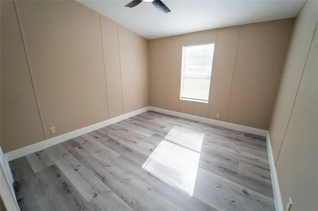 a view of empty room with wooden floor and fan