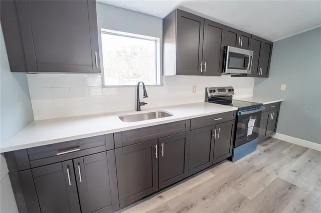 a kitchen with stainless steel appliances granite countertop a sink a stove and microwave