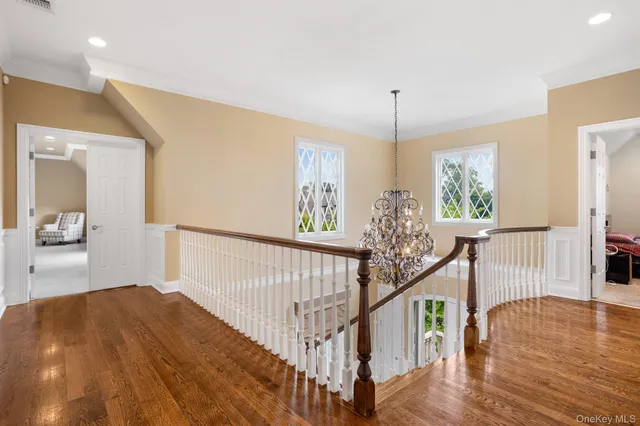 a view of a hallway to room with wooden floor and windows