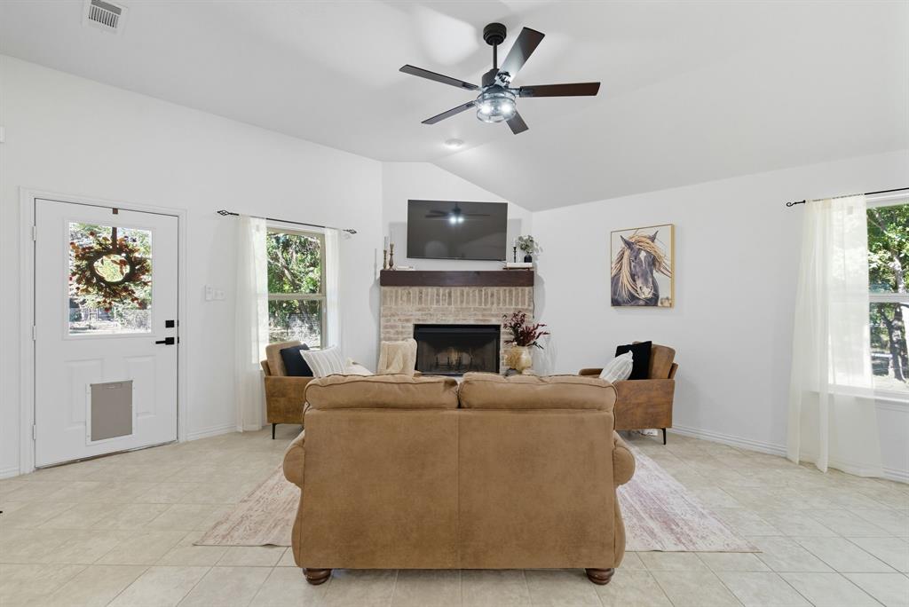 104 Candis Court Springtown, TX 76082 - Photo 16 of 40 a living room with furniture a flat screen tv and a fireplace