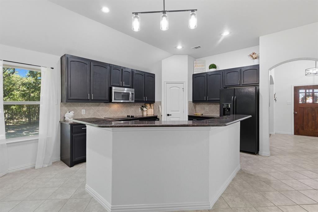 104 Candis Court Springtown, TX 76082 - Photo 9 of 40 a kitchen with stainless steel appliances granite countertop a refrigerator stove microwave and sink