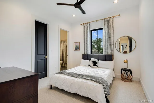 a bedroom with a bed a mirror and a large window