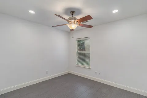 an empty room with window and ceiling fan